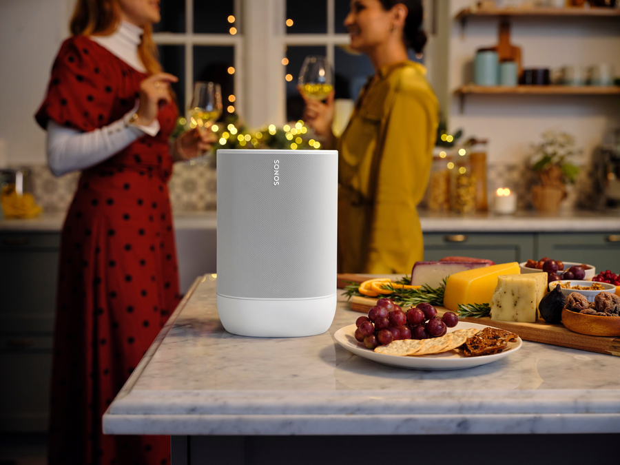 Sonos speaker on a kitchen counter playing music during a holiday gathering with friends.